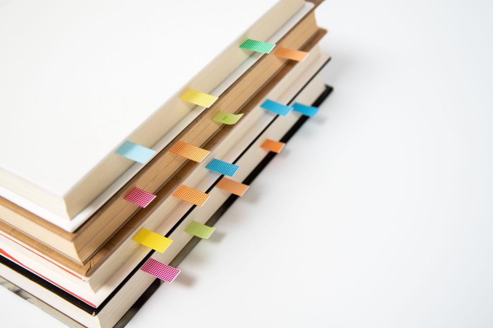 Stack of books bookmarked with sticky page markers.