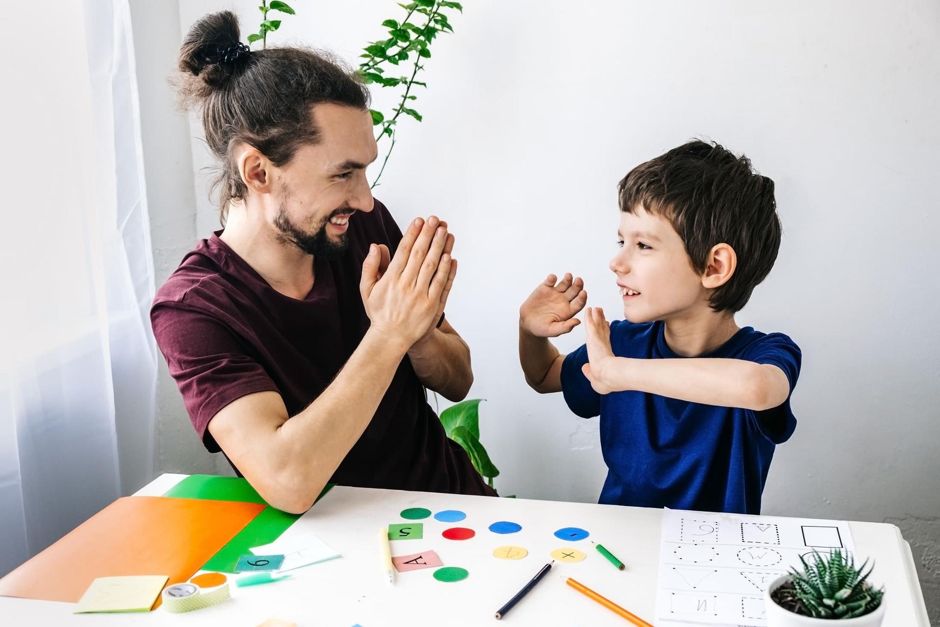 Counselor and a young, happy boy working together during educational therapy.
