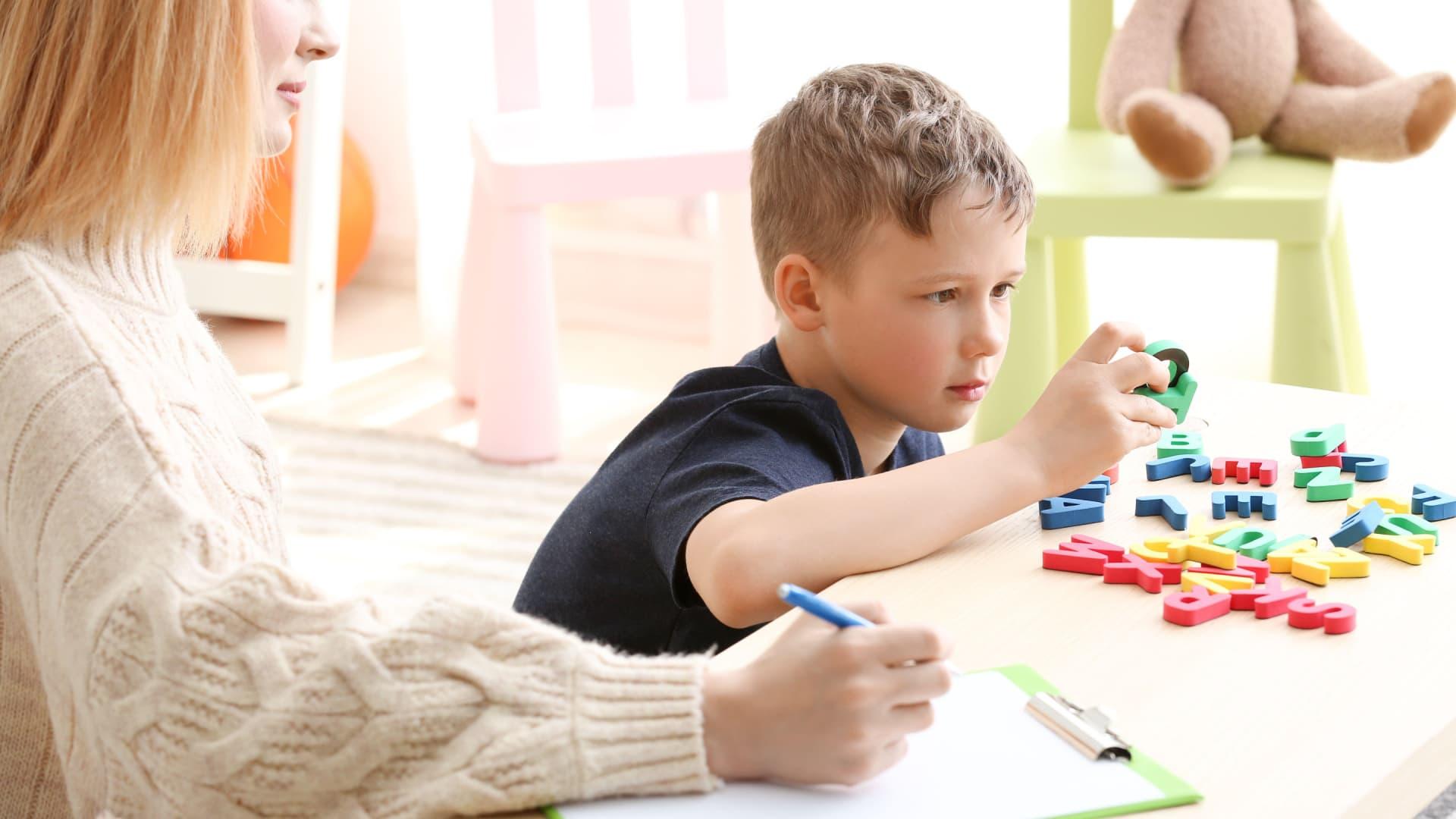 Educational therapist working with boy who is looking at letters.