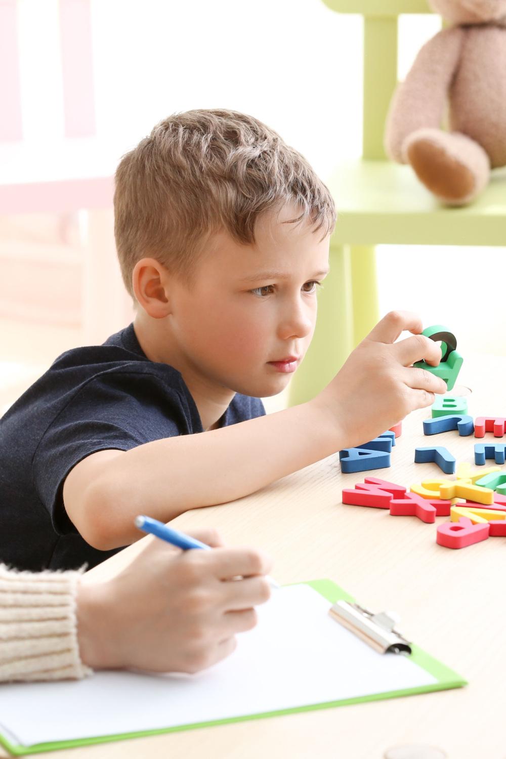 Boy looking at magnetic letters during educational therapy.