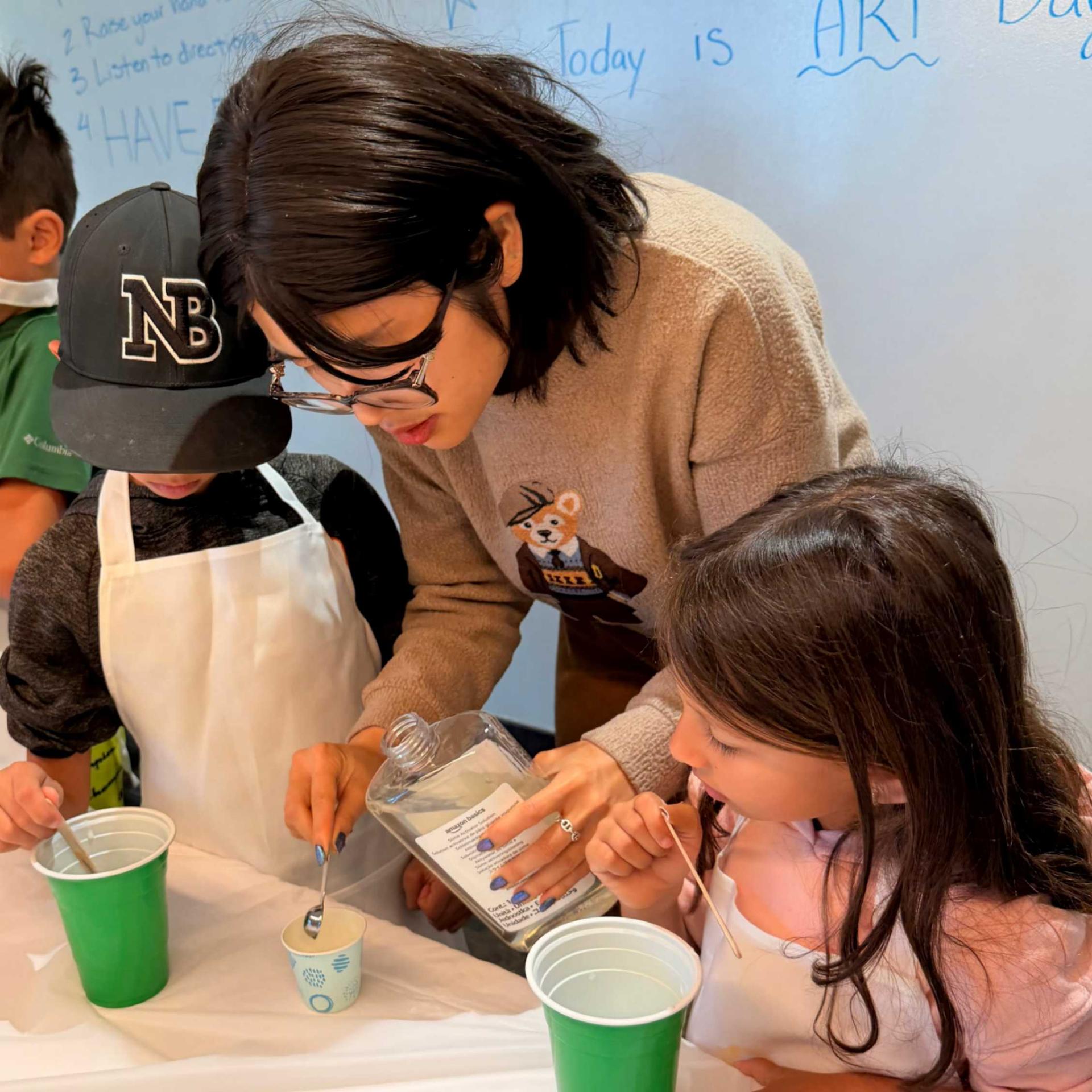 Two students and an instructor mixing soap into a cup.