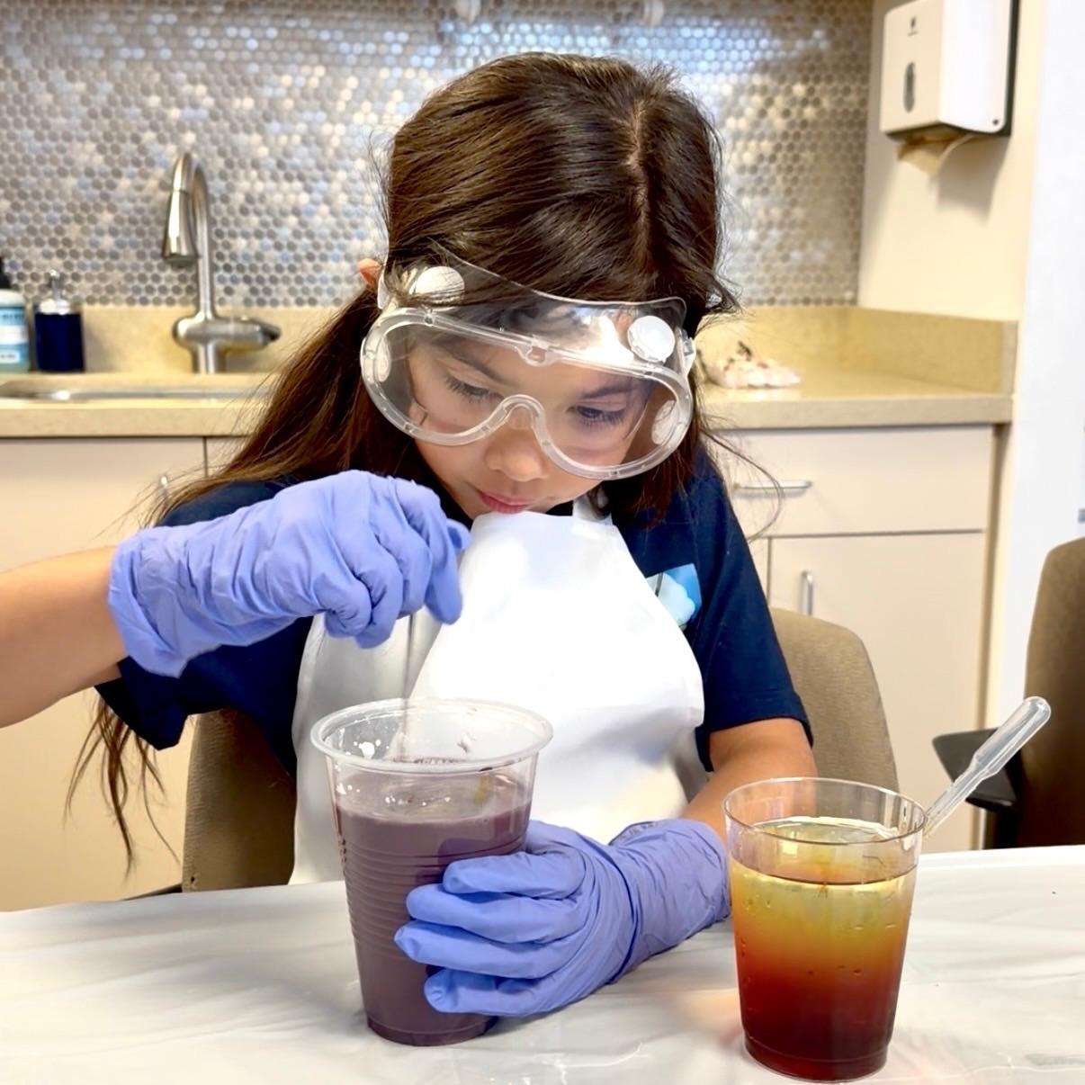 Student wearing safety goggles and mixing different liquids together.