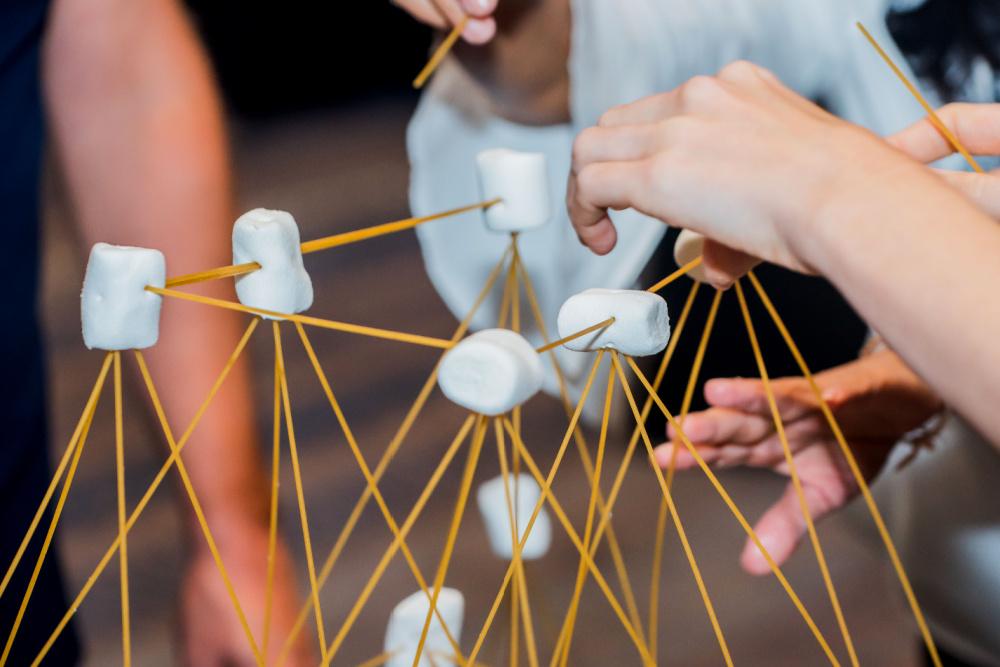 A team of students building a structure out of pasta noodles and marshmallows.