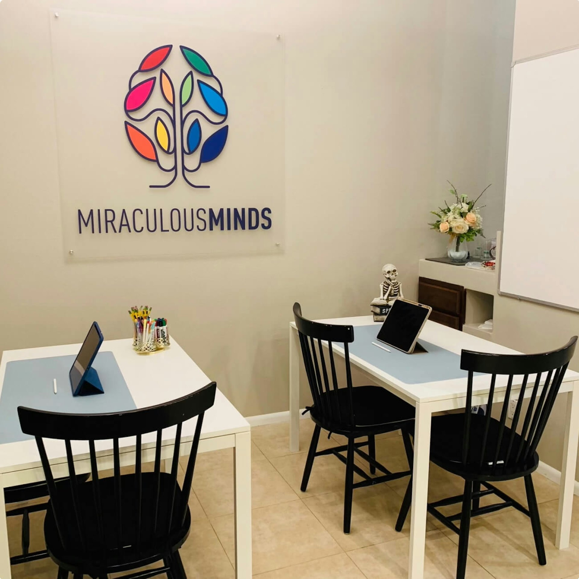 A tutoring classroom with a sign of “Miraculous Minds” logo on the wall.