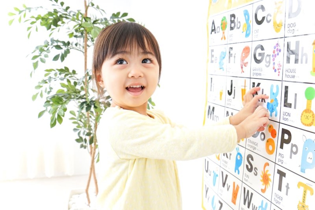 A girl pointing to a letter on an alphabet chart