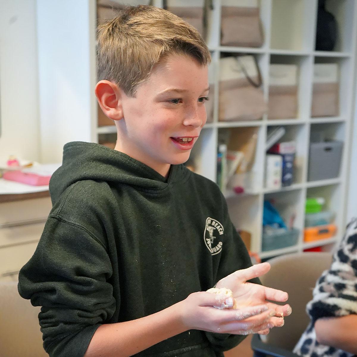 Boy holding dough in his hand.