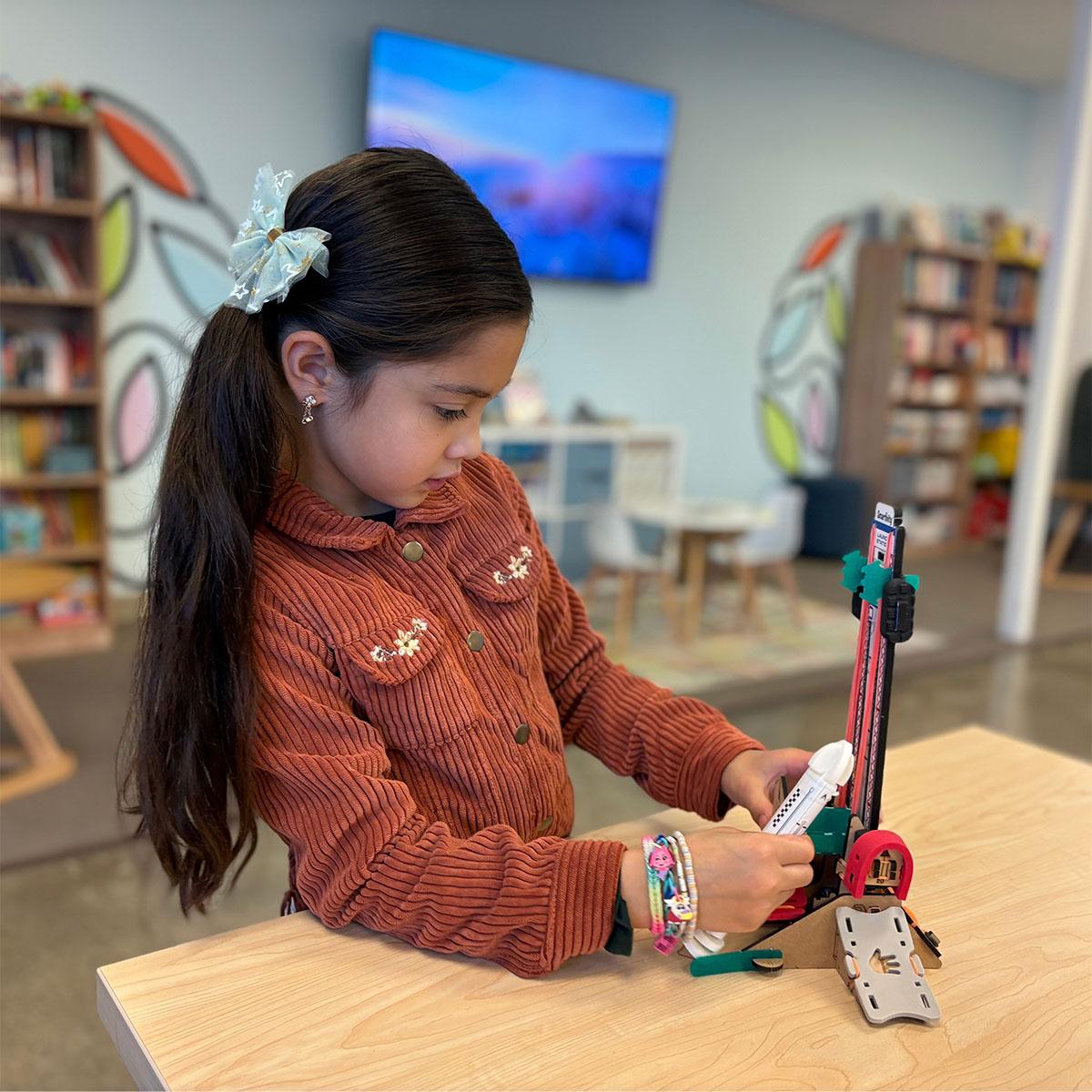 Young girl placing foam rocket onto launcher.