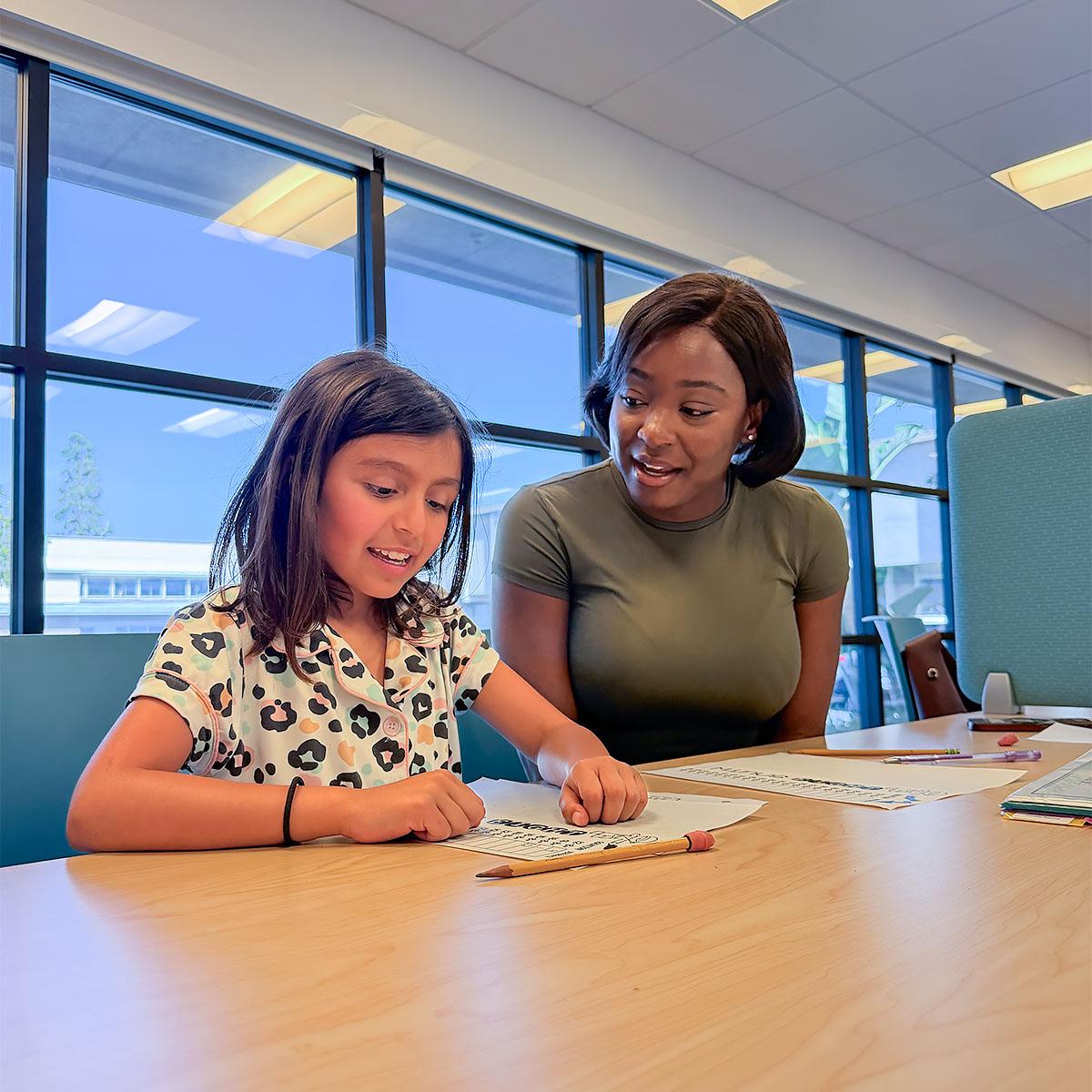 Student and teacher working on math facts at a desk.