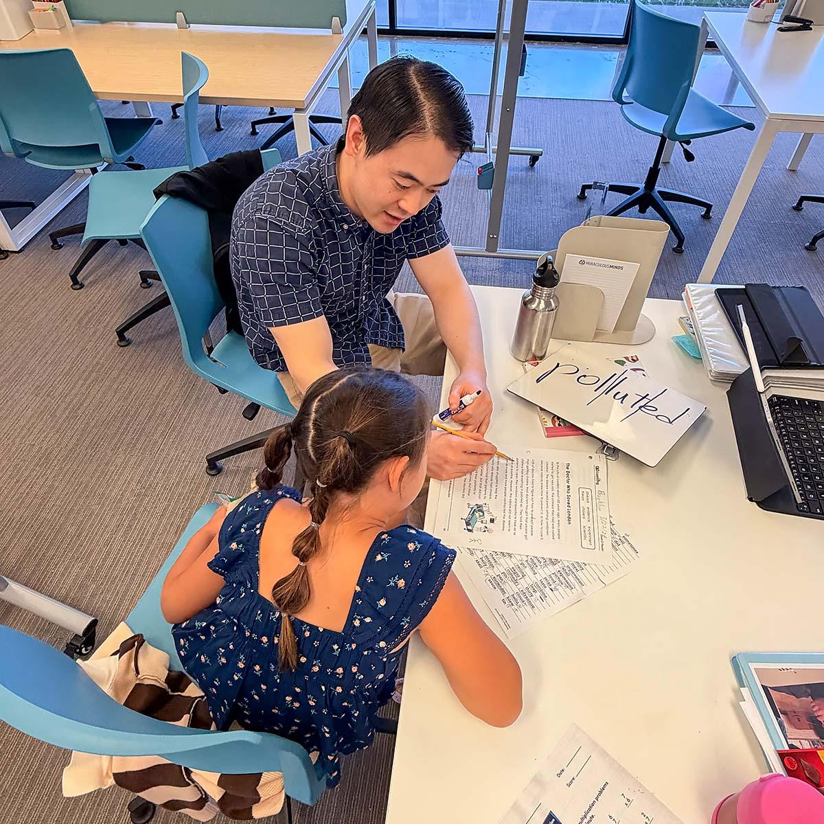 A teacher and student working on ELA worksheets.